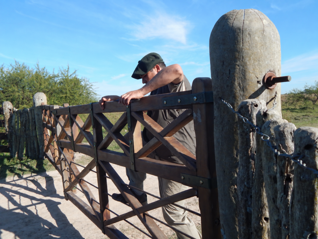 Hombre abriendo una tranquera en un establecimiento rural